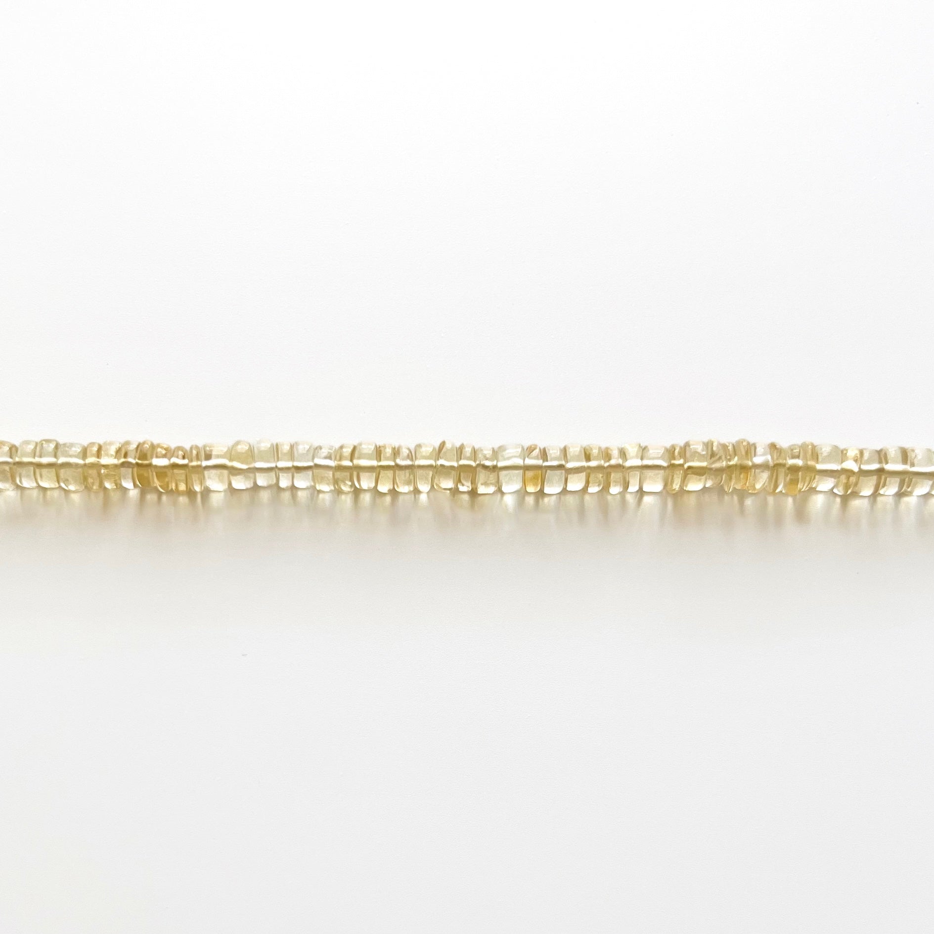 Close up strand of citrine beaded gemstone necklace with golden yellow orange smooth rondelle beads that are translucent in color