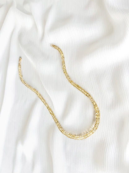 Citrine beaded gemstone necklace with golden yellow orange smooth rondelle beads and 14k gold filled or solid gold clasp with a minimalist design on a soft white fabric background