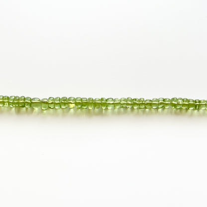 Close up of strand of green peridot beaded gemstone necklace with smooth rondelle beads