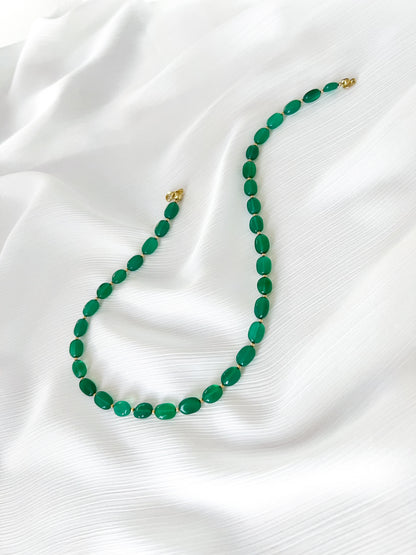 Green onyx beaded gemstone necklace with smooth oval beads, gold filled accents and finished with gold clasp on a soft white fabric background