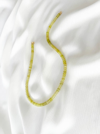 Lemon jade beaded gemstone necklace with smooth disc rondelle beads and sparkling Japanese seed bead accents, finished with 14k gold filled accent beads and clasp on a soft white fabric background
