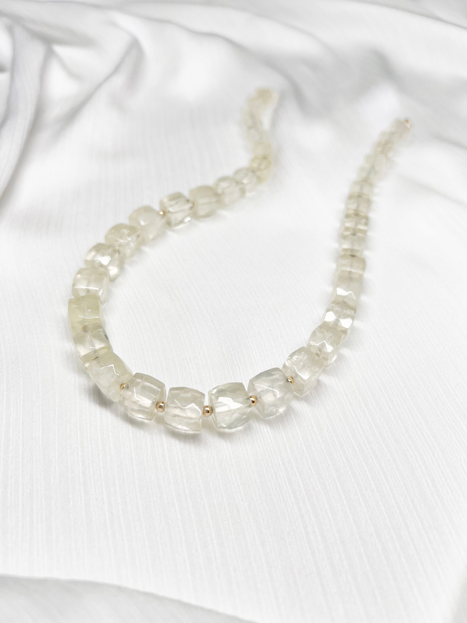 Lemon Quartz beaded gemstone necklace with light yellow faceted cube beads and 14k gold filled clasp and accent beads with a minimalist design on a soft white fabric background