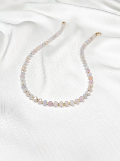 Dainty morganite beaded gemstone necklace with soft pastel hues of blush pink, peach, blues and green, with faceted rondelle beads finished with 14k gold filled accent beads and clasp on a soft white fabric background
