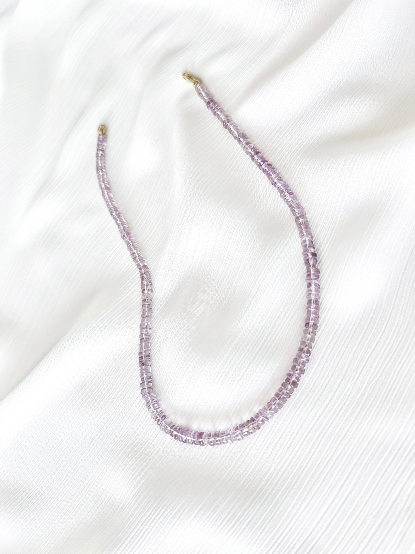 Pink Amethyst beaded gemstone necklace with translucent light purple smooth rondelle beads and 14k gold filled or solid gold clasp with a minimalist design on soft white fabric background