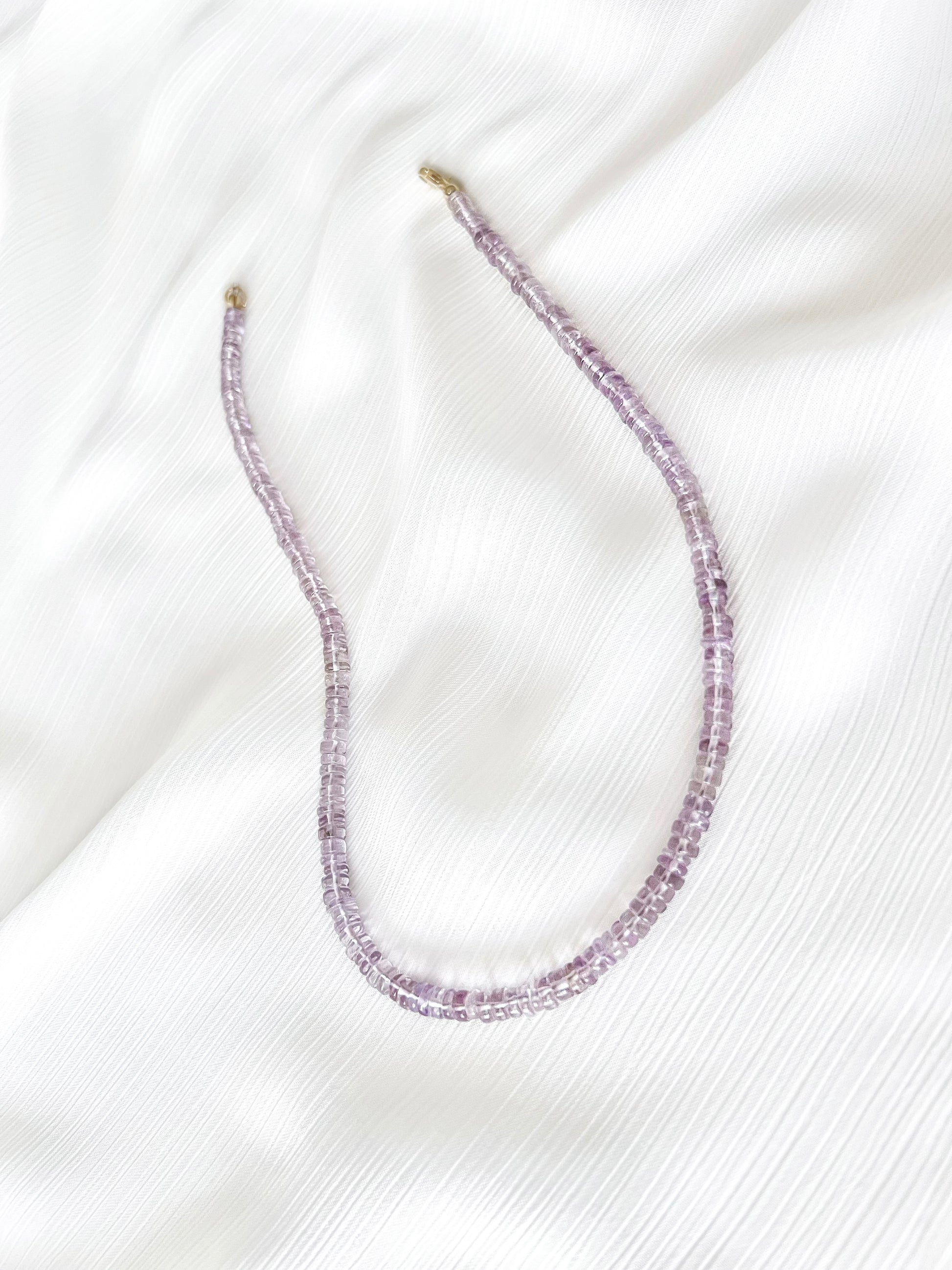 Pink Amethyst beaded gemstone necklace with translucent light purple smooth rondelle beads and 14k gold filled or solid gold clasp with a minimalist design on soft white fabric background
