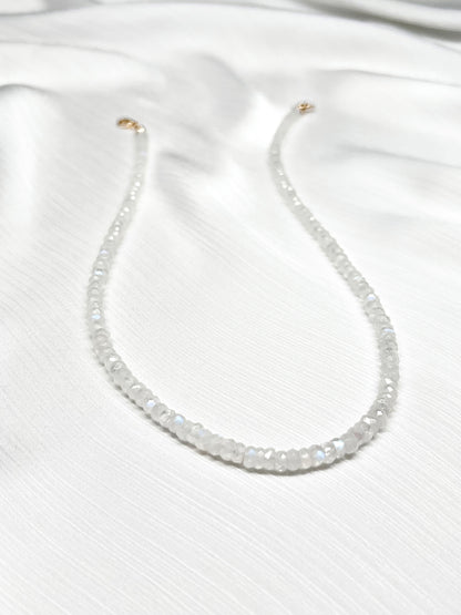 Rainbow moonstone beaded gemstone necklace with white faceted rondelle beads and 14k solid gold or gold filled clasp with minimalist design on a soft white fabric background