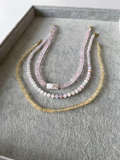Three gemstone beaded necklaces on a gray velvet tray: rose quartz faceted rondelle with keshi pearl center, pastel morganite faceted rondelle with gold filled accent beads, and citrine smooth rondelle with 14k solid gold or gold filled clasps