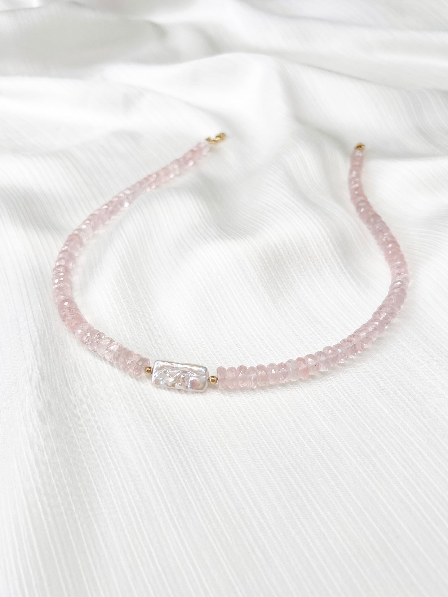 Rose Quartz beaded gemstone necklace with freshwater keshi pearl and pink faceted rondelle beads and 14k gold filled or solid gold clasp with minimalist design on a soft white fabric background