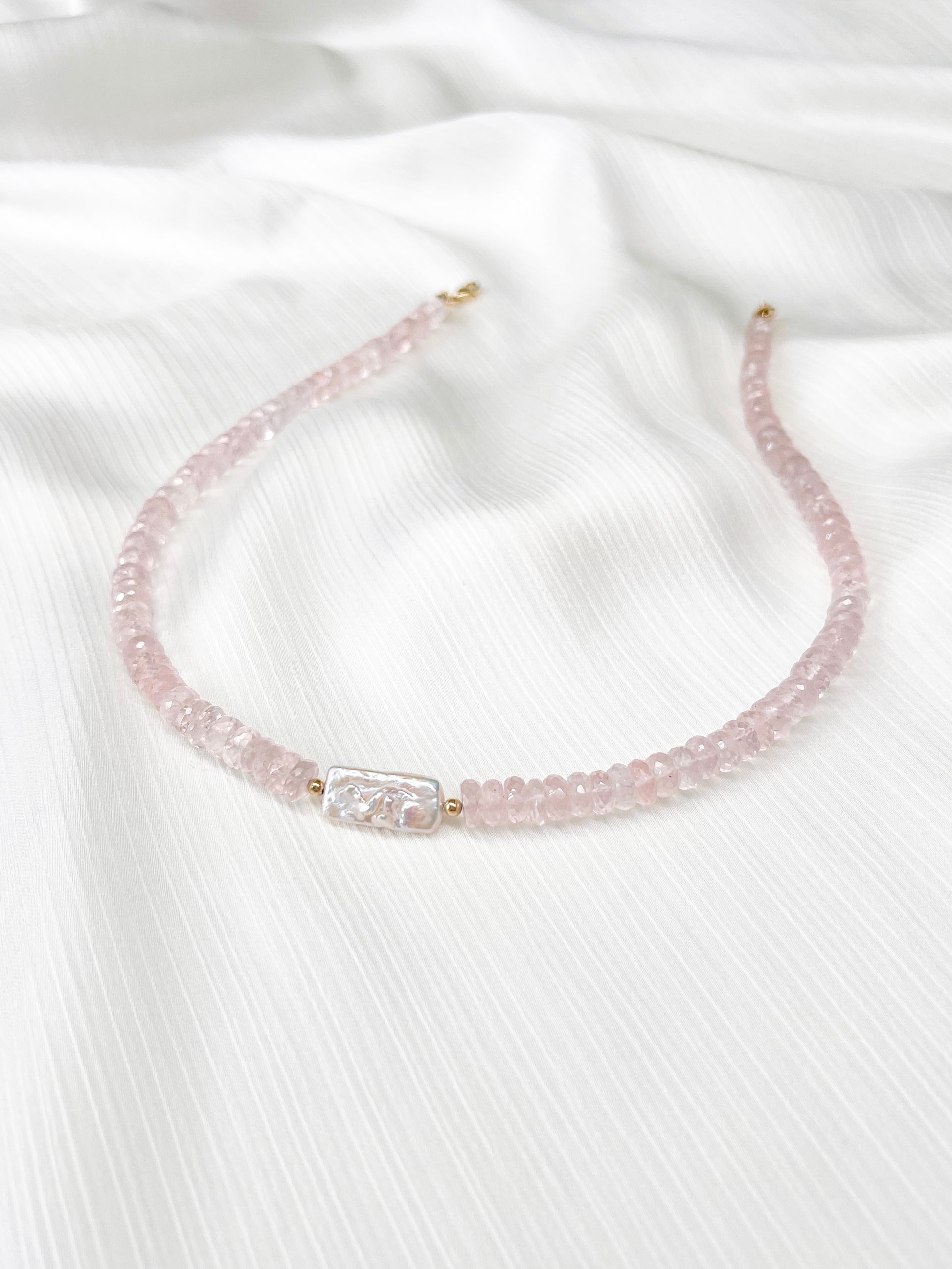 Rose Quartz beaded gemstone necklace with freshwater keshi pearl and pink faceted rondelle beads and 14k gold filled or solid gold clasp with minimalist design on a soft white fabric background