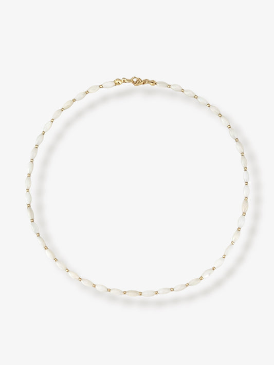 Dainty natural shell beaded necklace with white rice shaped shell beads and 14k gold filled accent beads and clasp. Minimalist layering necklace on a neutral background